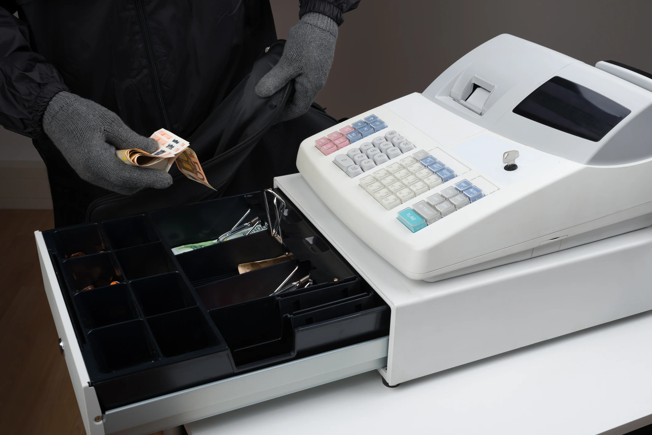 Ladrón abriendo caja registradora tradicional poco segura